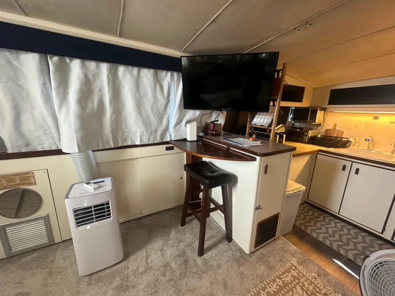 Slide: The Image of 1974 Bertram 42 Motor Yacht interior with TV, bar stool, and kitchen area. - 42