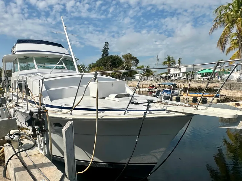 Slide: The Image of 1974 Bertram 42 Motor Yacht docked, featuring classic design and spacious deck under a blue sky. - 54