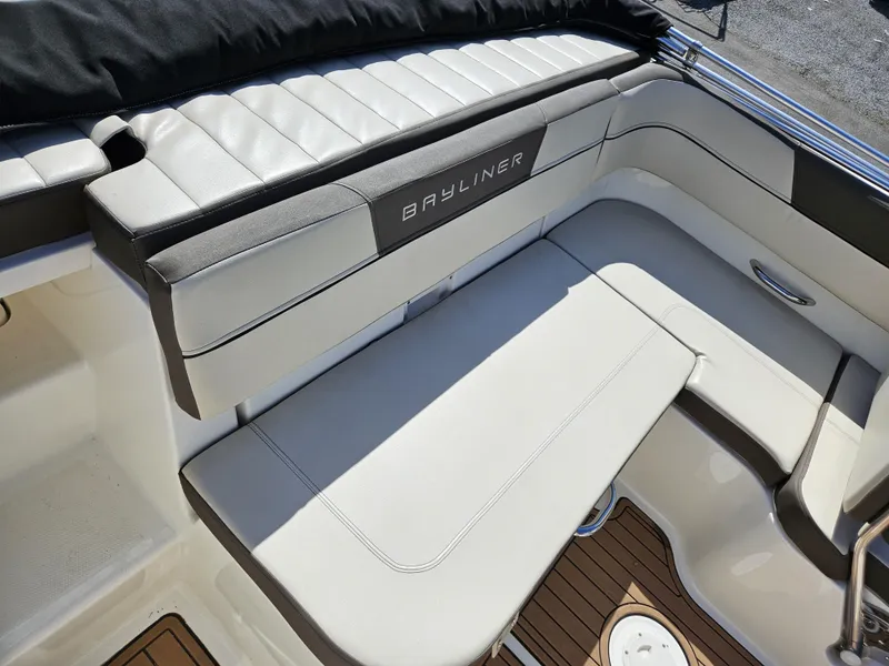 Slide: The Image of 2019 Bayliner VF5 boat interior with white cushioned seating and wood-style flooring. - 2