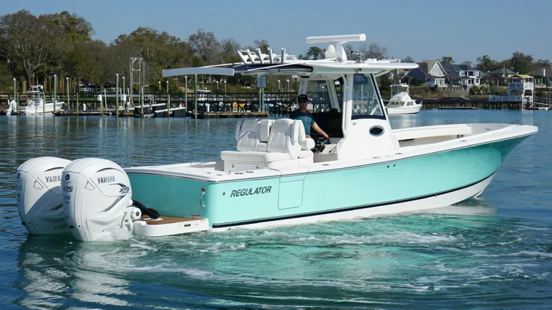 Slide: The Image of 2023 Regulator 34 boat cruising on a calm waterway with twin Yamaha engines. - 10