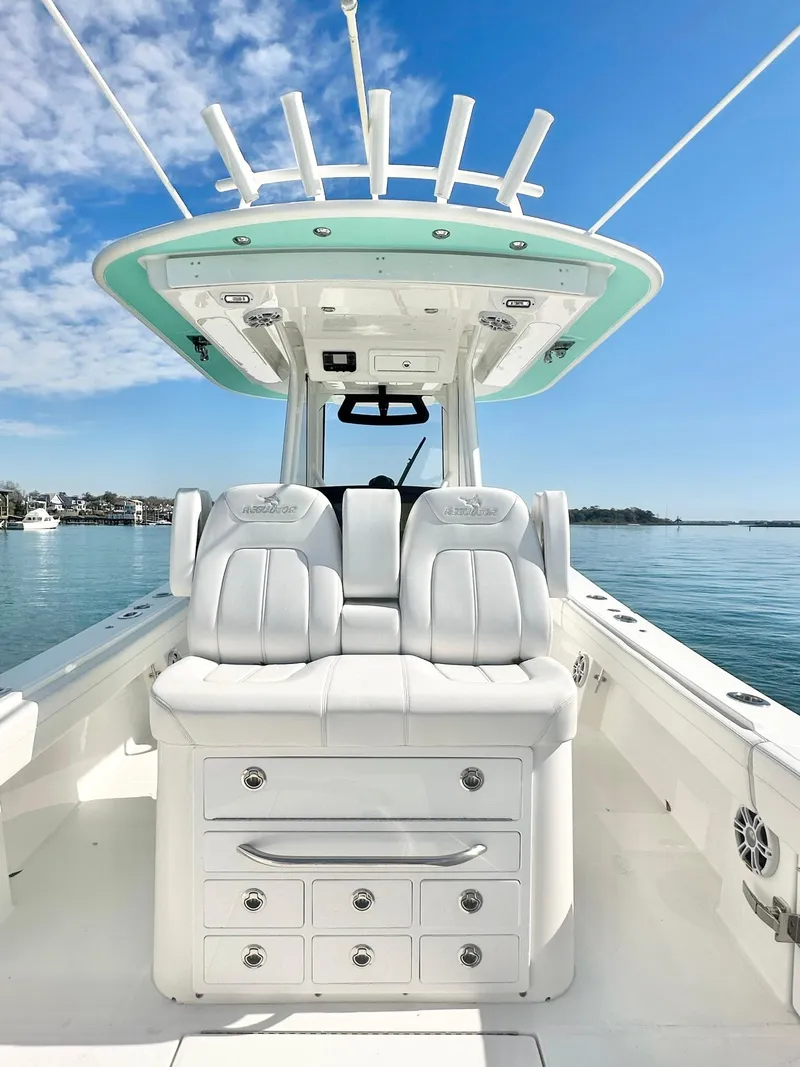 Slide: The Image of 2023 Regulator 34 boat interior with white seating and storage, under a clear blue sky. - 16
