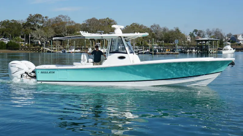 Slide: The Image of 2023 Regulator 34 boat on calm water, featuring sleek design and vibrant turquoise hull. - 5