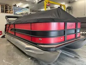 Slide: The Image of 2025 Bentley Pontoons Elite Swingback Bench 223, red and black, covered, in a showroom. - 1
