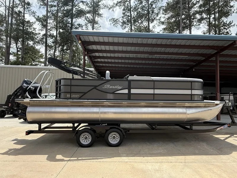 Slide: The Image of 2025 Bentley Pontoons Legacy Cruise XL 220 on trailer, parked under a metal canopy. - 2