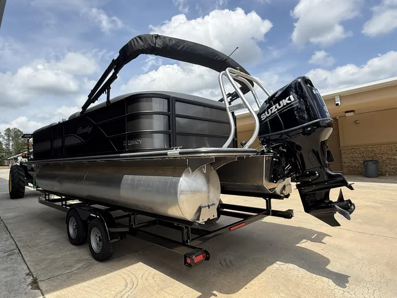 Slide: The Image of 2025 Bentley Pontoons Legacy Cruise XL 220 with Suzuki engine on trailer, under cloudy sky. - 3