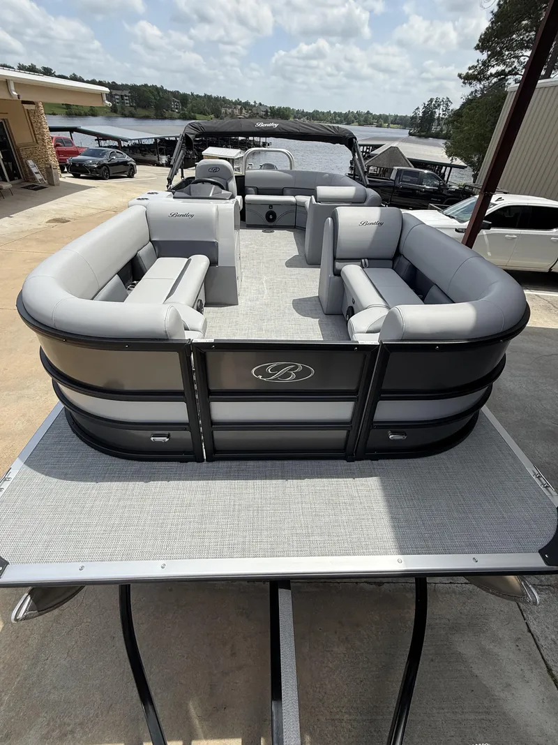 Slide: The Image of 2025 Bentley Pontoons Legacy Cruise XL 220, luxury pontoon boat with spacious seating, docked by a lake. - 8