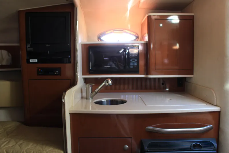 Slide: The Image of 2008 Sea Ray Sundancer interior with kitchenette, featuring sink, microwave, and storage cabinets. - 11