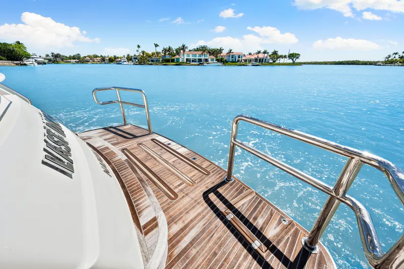 Slide: The Image of 2022 Riviera 5400 Sport Yacht on serene blue water with distant luxury homes. - 39