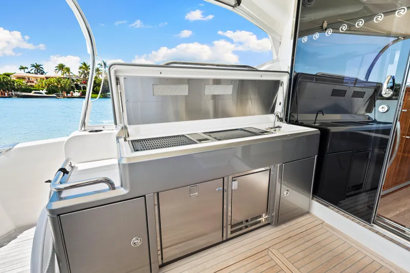 Slide: The Image of 2022 Riviera 5400 Sport Yacht outdoor kitchen with stainless steel appliances and scenic water view. - 46