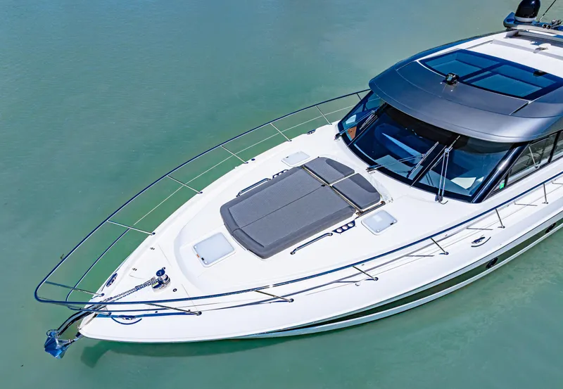 Slide: The Image of 2022 Riviera 5400 Sport Yacht on calm water, showcasing sleek design and spacious deck. - 8