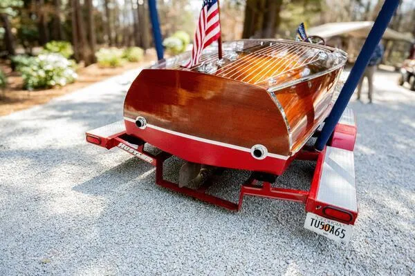 Slide: The Image of 1941 Hacker-Craft Deluxe boat on trailer, featuring polished wood and American flag. - 1