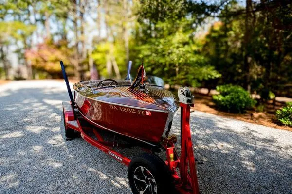 Slide: The Image of 1941 Hacker-Craft Deluxe boat on trailer in a wooded area. - 19