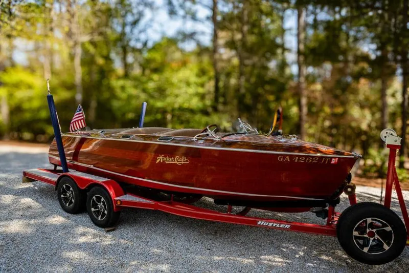 Slide: The Image of 1941 Hacker-Craft Deluxe boat on red trailer, surrounded by trees. - 20