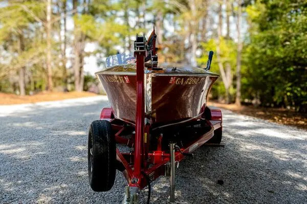 Slide: The Image of 1941 Hacker-Craft Deluxe boat on trailer, surrounded by trees. - 25