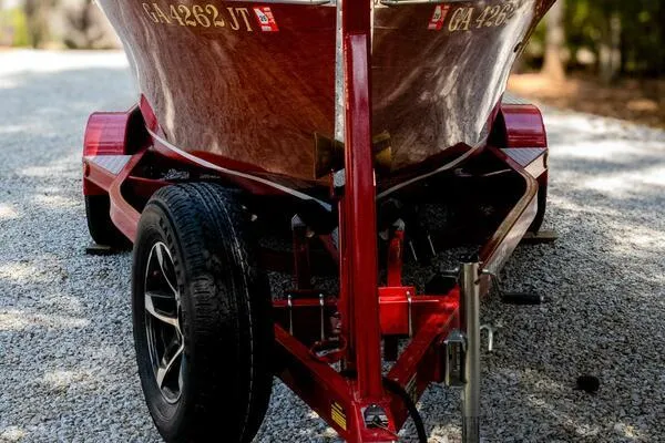 Slide: The Image of 1941 Hacker-Craft Deluxe boat on a red trailer, parked on gravel. - 30
