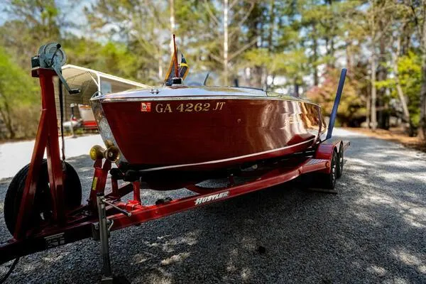 Slide: The Image of 1941 Hacker-Craft Deluxe boat on red trailer, surrounded by trees. - 33