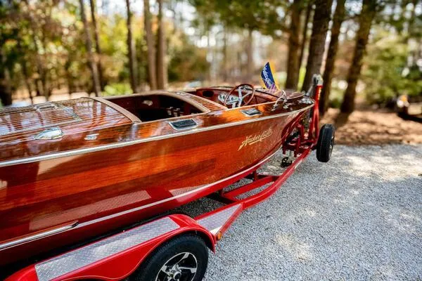 Slide: The Image of 1941 Hacker-Craft Deluxe wooden boat on a red trailer in a wooded area. - 35