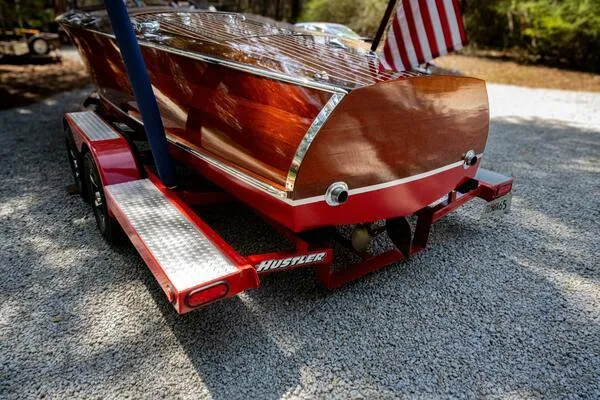 Slide: The Image of 1941 Hacker-Craft Deluxe boat on trailer with American flag, showcasing polished wood finish. - 36