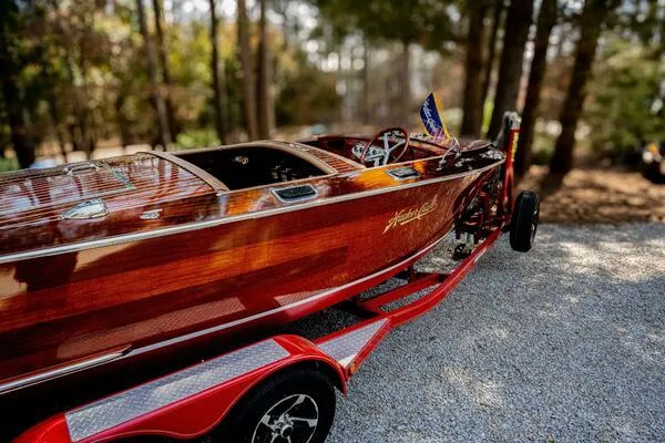 Slide: The Image of 1941 Hacker-Craft Deluxe boat on a red trailer in a wooded area. - 39