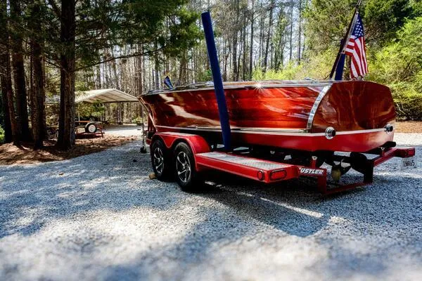 Slide: The Image of 1941 Hacker-Craft Deluxe boat on trailer, surrounded by trees, with American flag. - 4