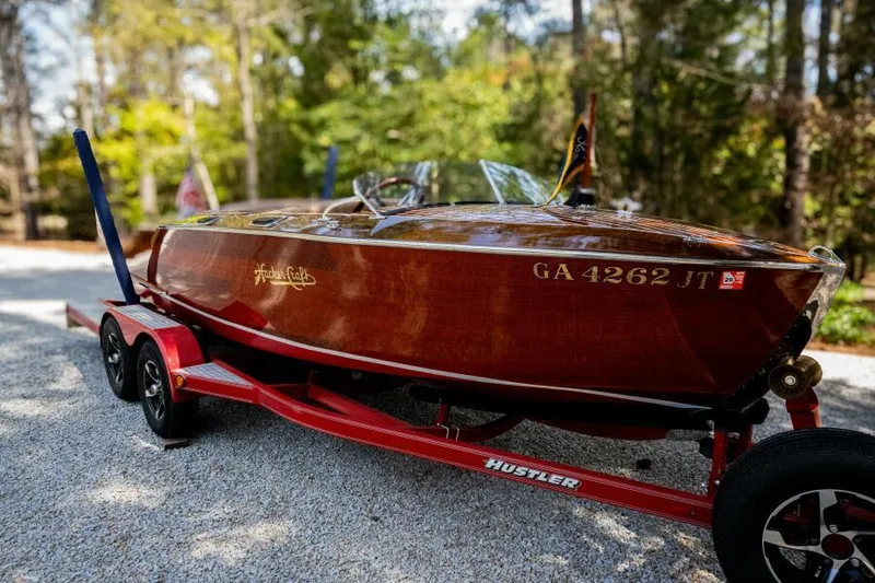 Slide: The Image of 1941 Hacker-Craft Deluxe boat on red trailer, surrounded by trees. - 43