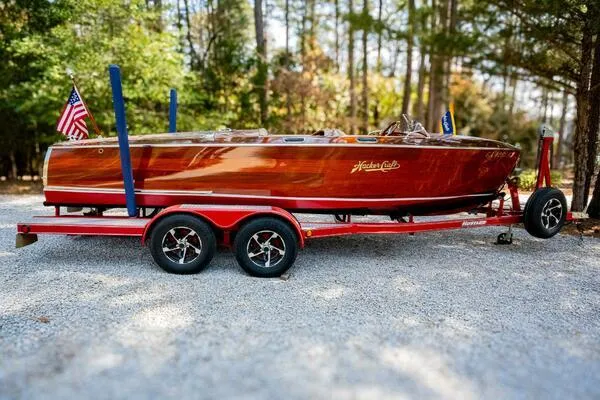 Slide: The Image of 1941 Hacker-Craft Deluxe boat on red trailer, surrounded by trees. - 46