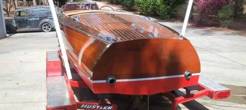 Slide: The Image of 1941 Hacker-Craft Deluxe boat on red trailer, showcasing polished wooden finish. - 49