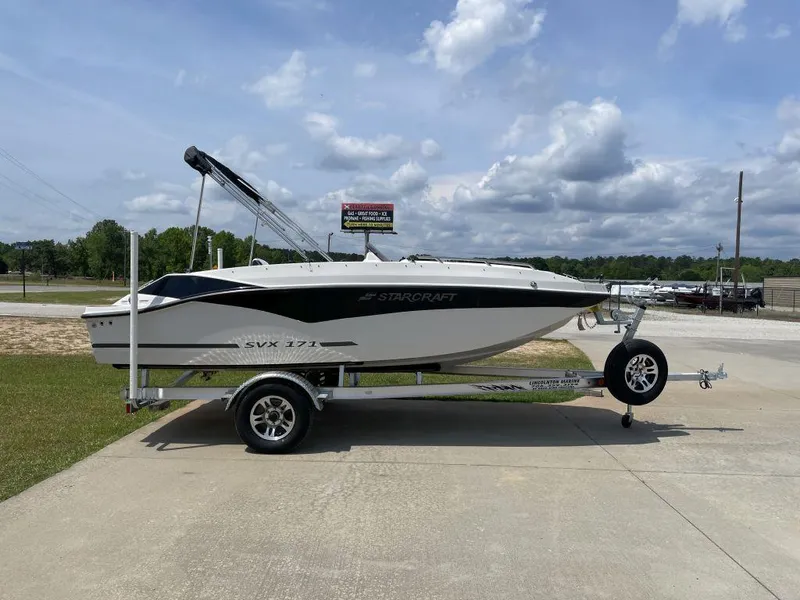 Slide: The Image of 2025 Starcraft SVX 171 OB boat on trailer, parked outdoors under cloudy sky. - 1