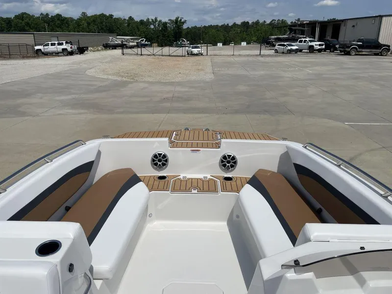 Slide: The Image of 2025 Starcraft SVX 171 OB boat interior with tan seating and speakers, parked outdoors. - 10
