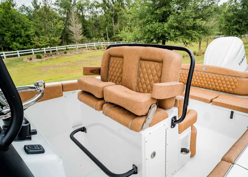 Slide: The Image of 2025 Sea Hunt Ultra 255 SE boat interior with tan leather seating and lush green background. - 18