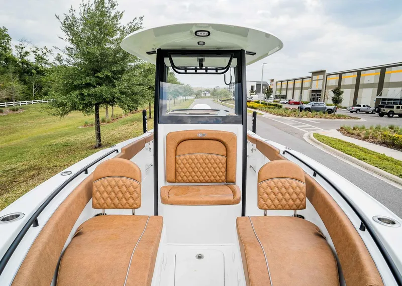 Slide: The Image of 2025 Sea Hunt Ultra 255 SE boat interior with tan leather seating, parked outdoors. - 28