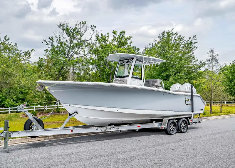 Slide: The Image of 2025 Sea Hunt Ultra 275 SE boat on trailer, parked on road with lush greenery. - 1