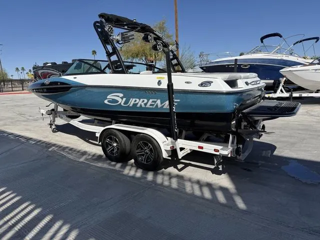 Slide: The Image of 2015 Supreme S226 boat on trailer, parked outdoors under clear blue sky. - 6