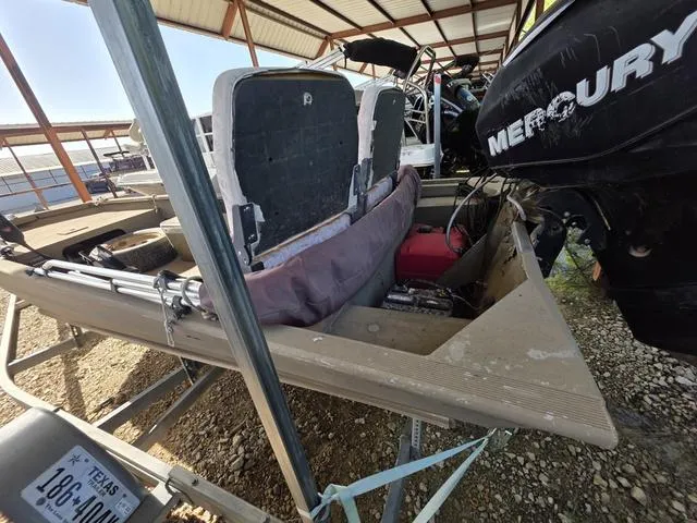 Slide: The Image of 2012 Tracker 1648 boat with Mercury engine, parked on a trailer under a metal roof. - 4