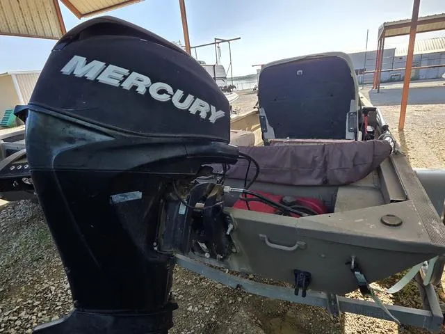 Slide: The Image of 2012 Tracker 1648 boat with Mercury outboard motor, parked under a metal canopy. - 6