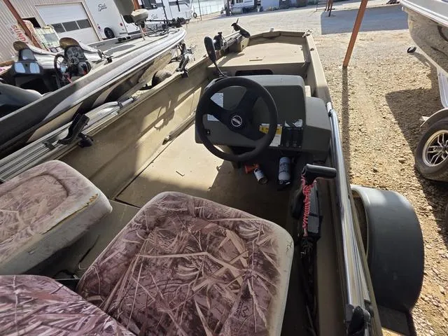 Slide: The Image of 2012 Tracker 1648 boat interior with camouflage seats and steering wheel, parked on gravel. - 8