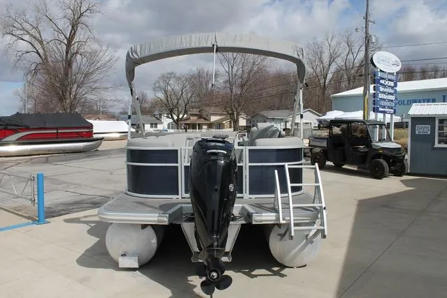 Slide: The Image of 2023 Bennington 21 SSR pontoon boat with outboard motor, parked at a marina. - 4