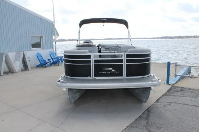 Slide: The Image of 2023 Bennington 21 SL pontoon boat docked by a lakeside marina. - 3