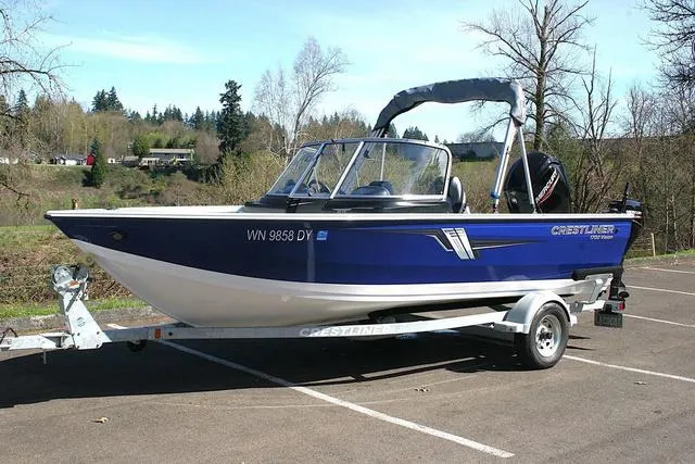 Slide: The Image of 2023 Crestliner 1700 Vision boat on trailer in a scenic outdoor setting. - 1