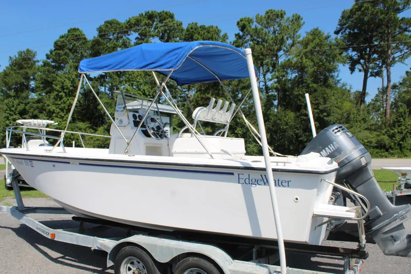 Slide: The Image of 1999 Edgewater 20cc boat with blue canopy on trailer, parked outdoors. - 17