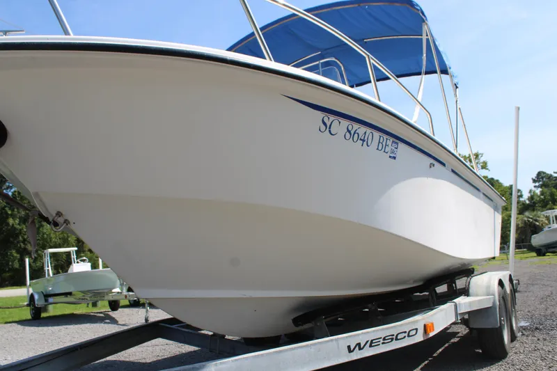 Slide: The Image of 1999 Edgewater 20cc boat on trailer with blue canopy, parked outdoors. - 18