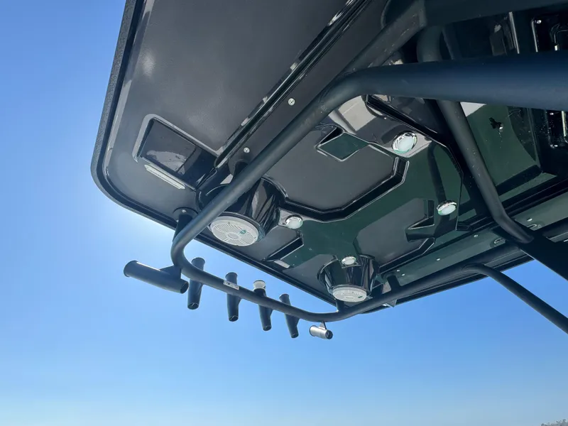 Slide: The Image of 2025 Crevalle 24 HCO boat roof with rod holders and lights against blue sky. - 34