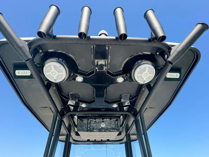 Slide: The Image of T-top of 2025 Crevalle 24 HCO boat with rod holders and speakers against blue sky. - 35