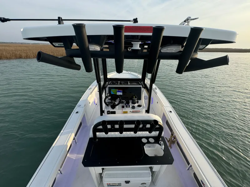 Slide: The Image of 2025 Crevalle 24 HCO boat with T-top and fishing rod holders on calm water. - 48