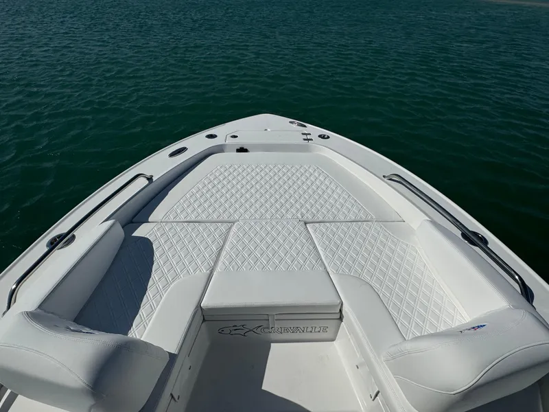 Slide: The Image of 2025 Crevalle 24 HCO boat with white cushioned seating on calm water. - 9
