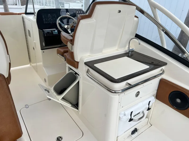 Slide: The Image of 2018 Scout 255 Dorado boat interior with helm, sink, and storage compartments. - 10