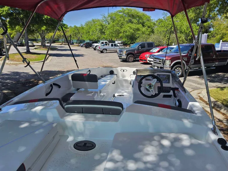 Slide: The Image of 2025 Tahoe T18 boat interior with red canopy, parked in a sunny lot. - 2