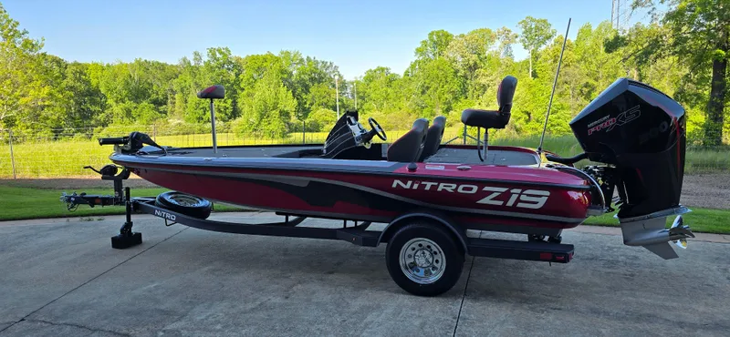 The Image of 2025 Nitro Z19 boat on trailer, parked outdoors with lush greenery background. - 0