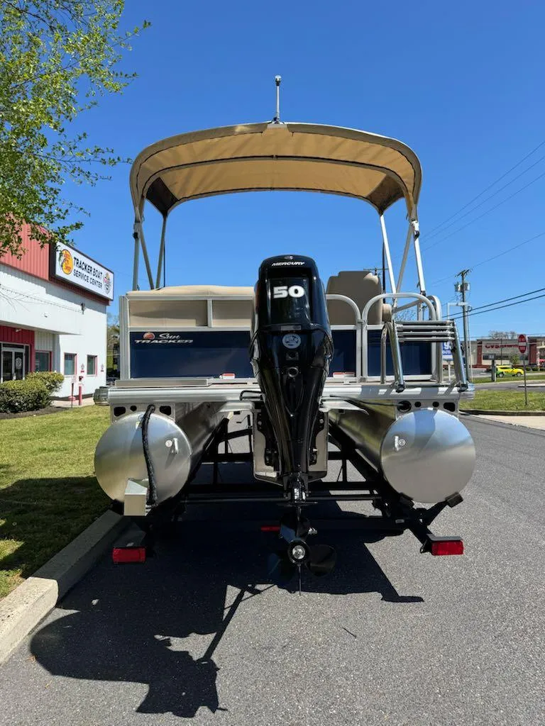 Slide: The Image of 2025 Sun Tracker Bass Buggy 16 XL Select pontoon boat with canopy and motor, parked outdoors. - 5
