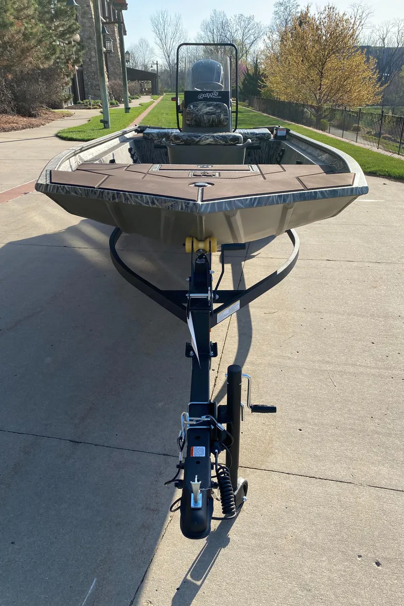 Slide: The Image of 2025 Tracker Grizzly 1860 CC boat on trailer, parked on a sunny driveway. - 2